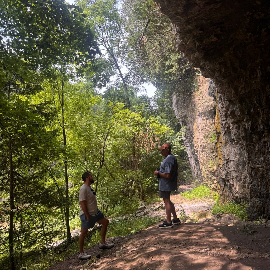 Two men hiking a wooded canyon trail